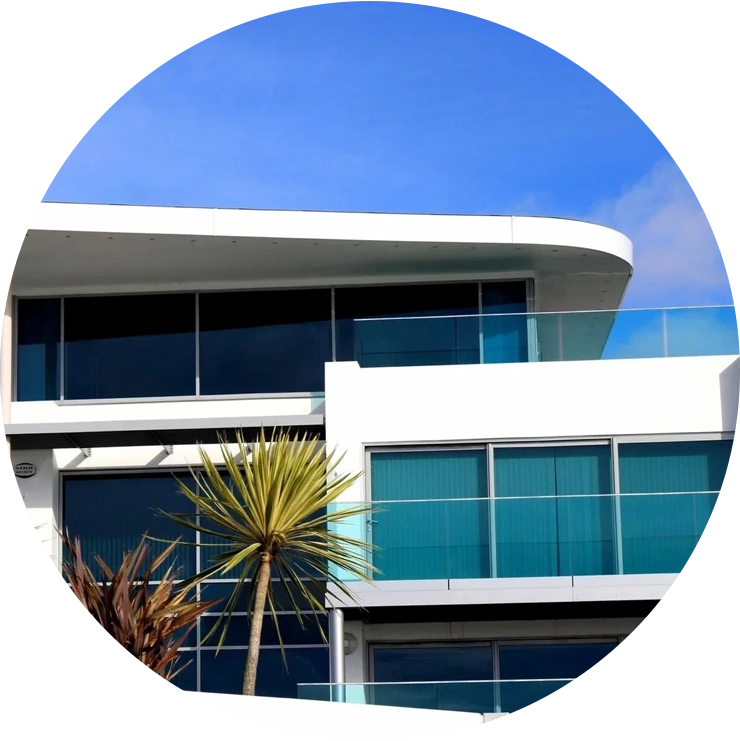 A palm tree in front of a building with glass windows.