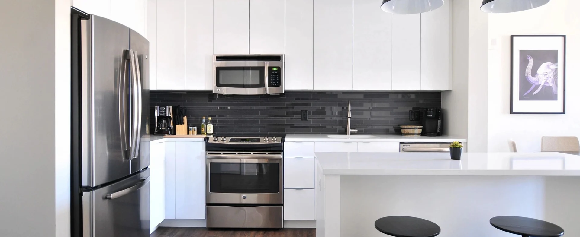 A kitchen with white cabinets and black tile.